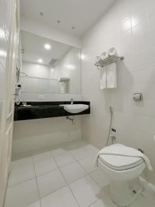 a white bathroom with a toilet and a sink at Hotel Cordialle in São Roque