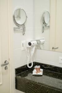 a bathroom with a hair dryer and a mirror at Hotel Cordialle in São Roque