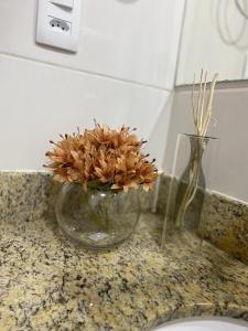 a glass vase with flowers in it on a counter at Apto Luxo completo 3 quartos em Guriri 300 mts da praia Wi-fi grátis in Guriri