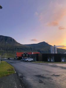 a building with a car parked in front of a mountain at Hótel Austur in Reyðarfjörður