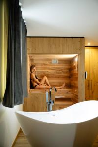 a woman is sitting in a sauna in a bathroom at B&B Relais Dolomiti in Bedollo