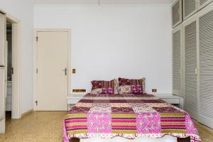 Bela's Suítes- 60 m da praia de Barequeçaba في باريكيسابا: غرفة نوم مع سرير مع بطانية ملونة عليه