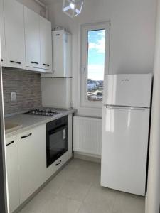 a white kitchen with a refrigerator and a window at Lovely 1-room apartment in Popeşti-Leordeni