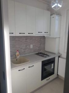 a kitchen with white cabinets and a sink at Lovely 1-room apartment in Popeşti-Leordeni