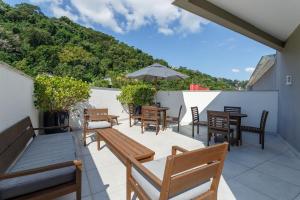 a patio with tables and chairs and an umbrella at Apto no centro com piscina RRI103 in Florianópolis