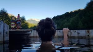 uma pessoa numa piscina com duas garrafas de cerveja em Peuma Lodge Patagonia em Futaleufú