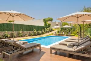 a swimming pool with lounge chairs and umbrellas at BFRESH Hotel - Padel, Pool & Fitness - Adults Only in Porto