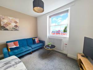 uma sala de estar com um sofá azul e uma janela em Margaret's Loft em Cheltenham