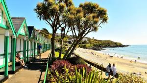 a beach with palm trees and people on the beach at Central Mumbles Apartment, Properties By O & G, Incredible Location, Sleeps 4! in The Mumbles