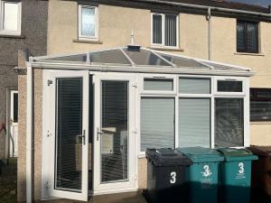a screened in greenhouse with two trash cans in front of a building at Lanarkshire entire house sleeps 6, contractors, trade stays in Kilsyth