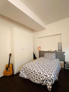 Un dormitorio con una cama y una guitarra. en Grazioso&strategico monolocale, en Bolonia