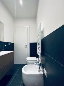 baño azul y blanco con 2 aseos y lavamanos en Grazioso&strategico monolocale, en Bolonia