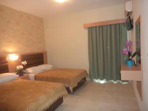 um quarto de hotel com duas camas e uma janela em Hotel Dioni em Paralia Katerinis