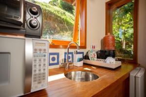 a kitchen counter with a sink and a microwave at Chalé Leopoldo-Nas Nuvens in São Bento do Sapucaí