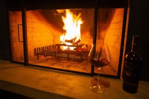a glass of wine and a fire in a fireplace at Chalé Leopoldo-Nas Nuvens in São Bento do Sapucaí