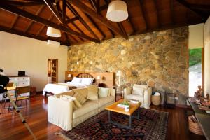 a living room with a couch and a stone wall at Chalé Leopoldo-Nas Nuvens in São Bento do Sapucaí