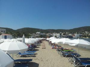 a group of chairs and umbrellas on a beach at Pericles Studios in Agia Marina Aegina