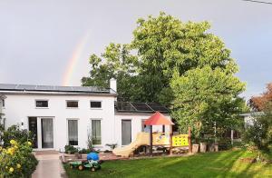 a house with a playground and a rainbow in the background at Chalet im Spiel- und Obstgarten in Keidelheim