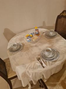 a white table with two cups and plates on it at Village home in Chios