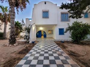 a house with a checkered floor in front of a building at Maison Nassif in Djerba