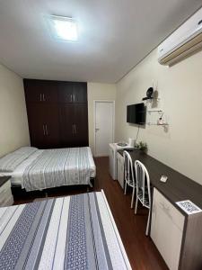 um quarto com uma cama, uma secretária e uma cozinha em POUSADA Dona Ziza em Maringá