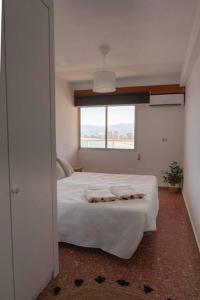 a bedroom with a white bed and a window at Florazar 2, 1a línea, piscina. in Cullera