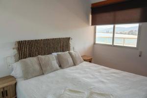 a bedroom with a large white bed with a window at Florazar 2, 1a línea, piscina. in Cullera