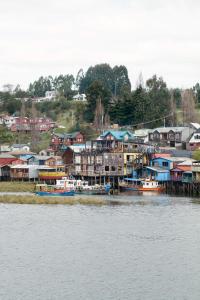 Palafito 1326 Hotel Boutique Chiloé في كاسترو: مجموعة منازل وقوارب على الماء