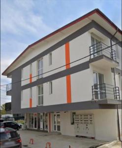 a large white building with an orange stripe on it at Lovely 1-room apartment self check-in in Popeşti-Leordeni