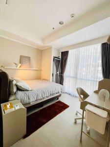 a bedroom with a bed and a desk and a window at [300m to PRJ] Expo Friendly 2BR in Jakarta