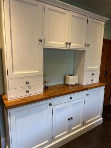 a kitchen counter with white cabinets and a toaster on it at Sugar Plum Cottage in Conisbrough