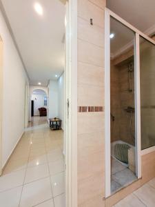 un pasillo con una puerta de cristal que conduce a una ducha a ras de suelo en Maison Nassif, en Djerba