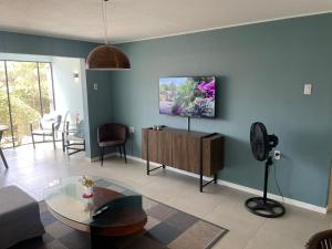 een woonkamer met een tv aan een blauwe muur bij Kas di BaMi A-186 op Seru Coral Resort - Ruim appartement met groot zwembad en tropische tuin in Willemstad