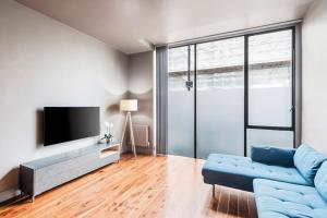 uma sala de estar com um sofá azul e uma televisão em Modern Spacious Apartment in Islington em Londres