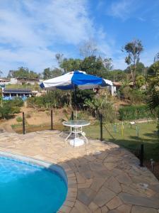 a table and an umbrella next to a swimming pool at Chácara Recanto do Sol in Mogi das Cruzes +40 photos