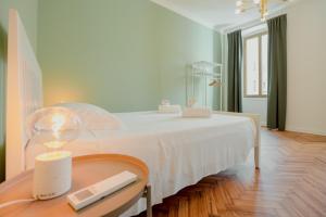 um quarto com uma cama branca e uma mesa com um candeeiro em Casa Settefontane em Trieste