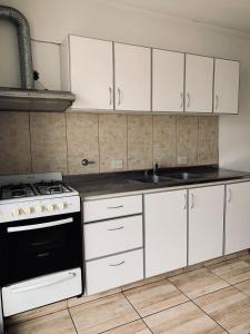 a kitchen with white cabinets and a stove top oven at Sarmiento - 1A in Concordia