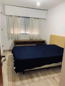 Un dormitorio con una cama azul y una ventana en Sarmiento - 1A en Concordia
