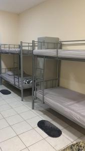 three bunk beds in a room with a tile floor at Rovers Boys Hostel Dubai Near Gold Souq Metro in Dubai