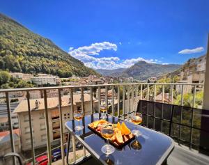 サン・クロードにあるLa Capucine - Lumineux avec balcon et parkingのバルコニーにテーブルとワイン1杯