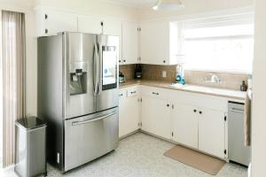 uma cozinha com um frigorífico de aço inoxidável e armários brancos em Follow the Leader em Houston