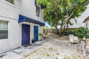 ein weißes Haus mit einer blauen Tür und einem Baum in der Unterkunft Bungalow King n Queen Bed 5m Wynwood Kitchen in Miami
