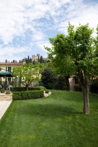 un césped verde con un árbol y un castillo en el fondo en Damaranto Residenza e Cucina, en Soave