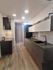 a large kitchen with white cabinets and a sink at Erdvi studija Spacious studio apartment Self check in in Vilnius