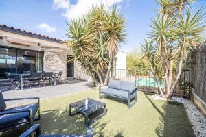 a patio with a couch and a table and palm trees at New Villa Oasis- Clim- Piscine privé- Cosy- famille TOP PROS SERVICESCONCIERGERIE in Saint-Gély-du-Fesc