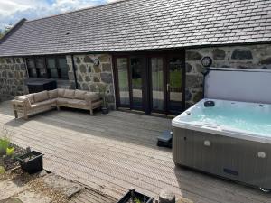 un bain à remous sur une terrasse en bois avec une maison dans l'établissement Barclay’s But n Ben, à Alford