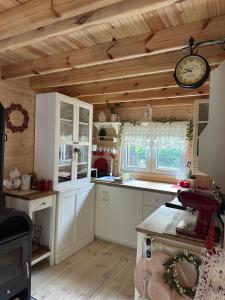 a kitchen with white cabinets and a clock on the wall at Chatka Jezioranka & bania 