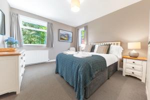a bedroom with a bed with a blue blanket at Colt Park Cottage in Ulverston