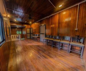 an empty room with wooden walls and tables and chairs at The River Village Retreat Kiulu in Tamparuli