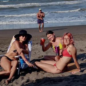 trzy kobiety w strojach kąpielowych siedzące na plaży w obiekcie La Morada, una ventana al golfo - Hotel boutique w mieście Monte Gordo
